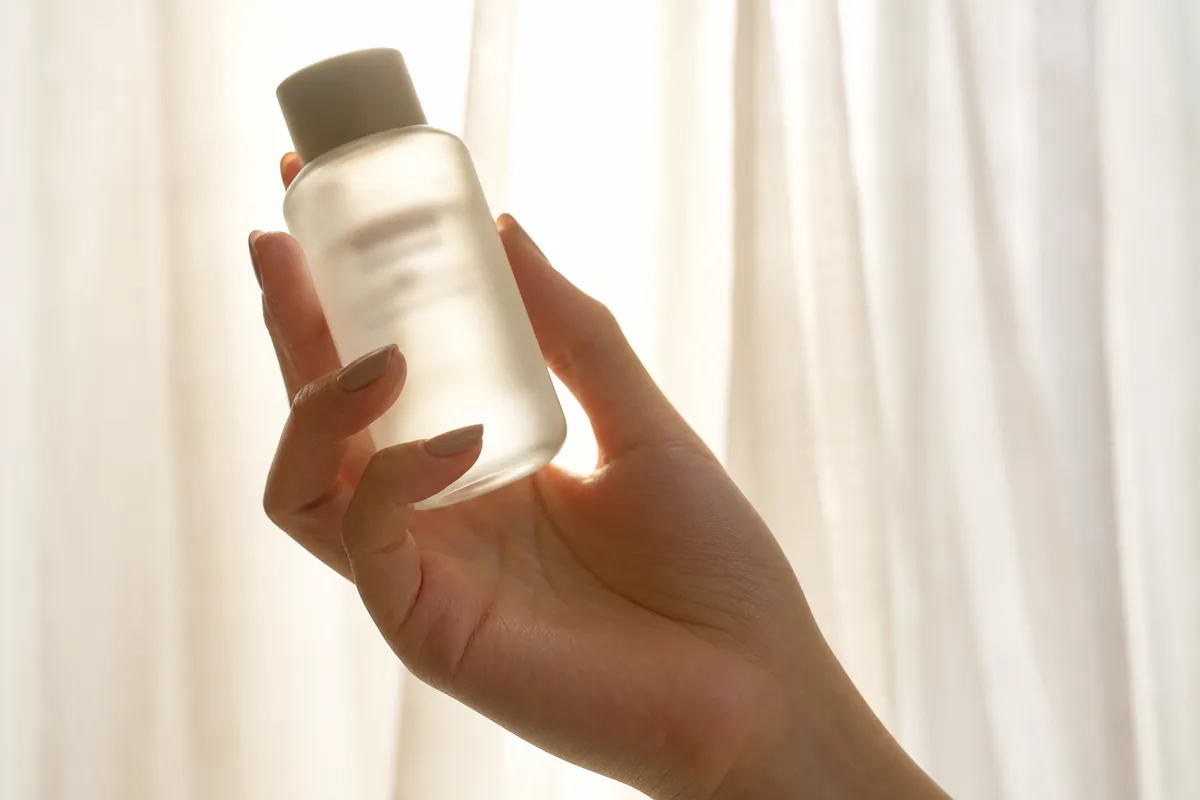 Étiquette d’un flacon cosmétique lue à la lumière naturelle près d’une fenêtre
